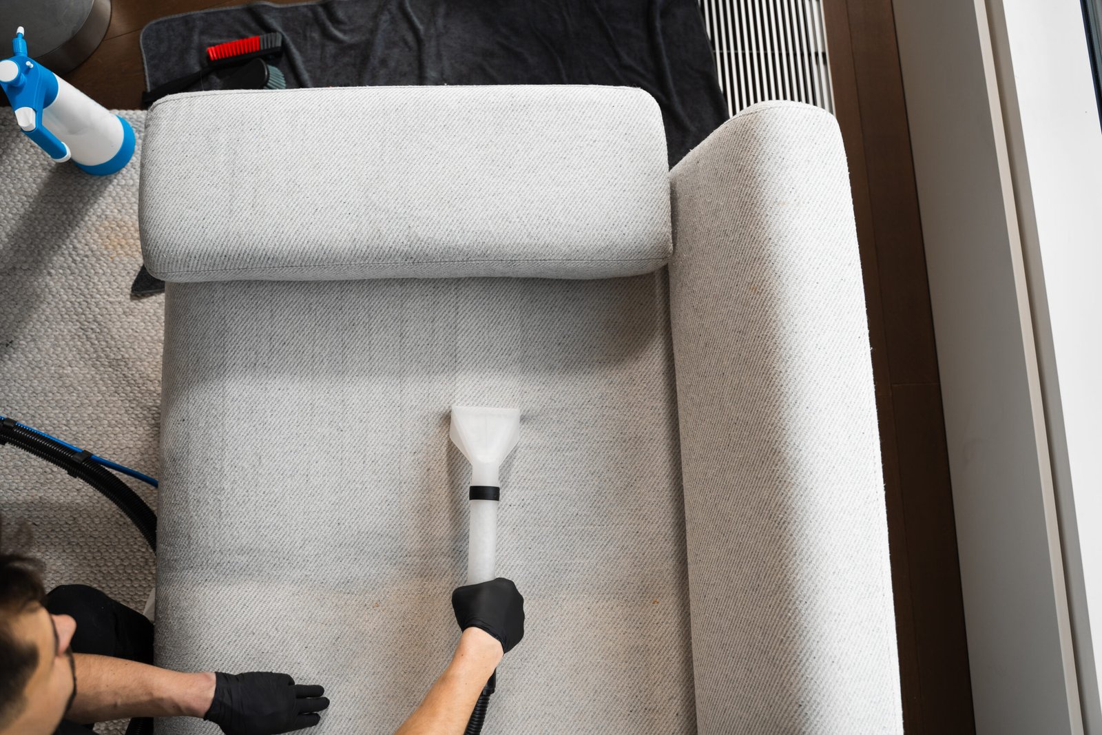 Refreshing sofa and cushions from dust and dirt with dry-cleaning extractor. Extracting dust and dirt, removing spots from sofa using extractor to clean upholstered furniture.